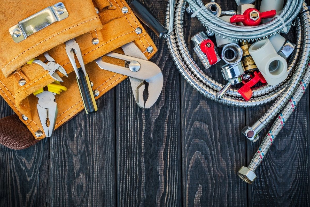 A variety of tools arranged on a wooden table, showcasing wrenches, screwdrivers, and pliers in a well-organized manner.