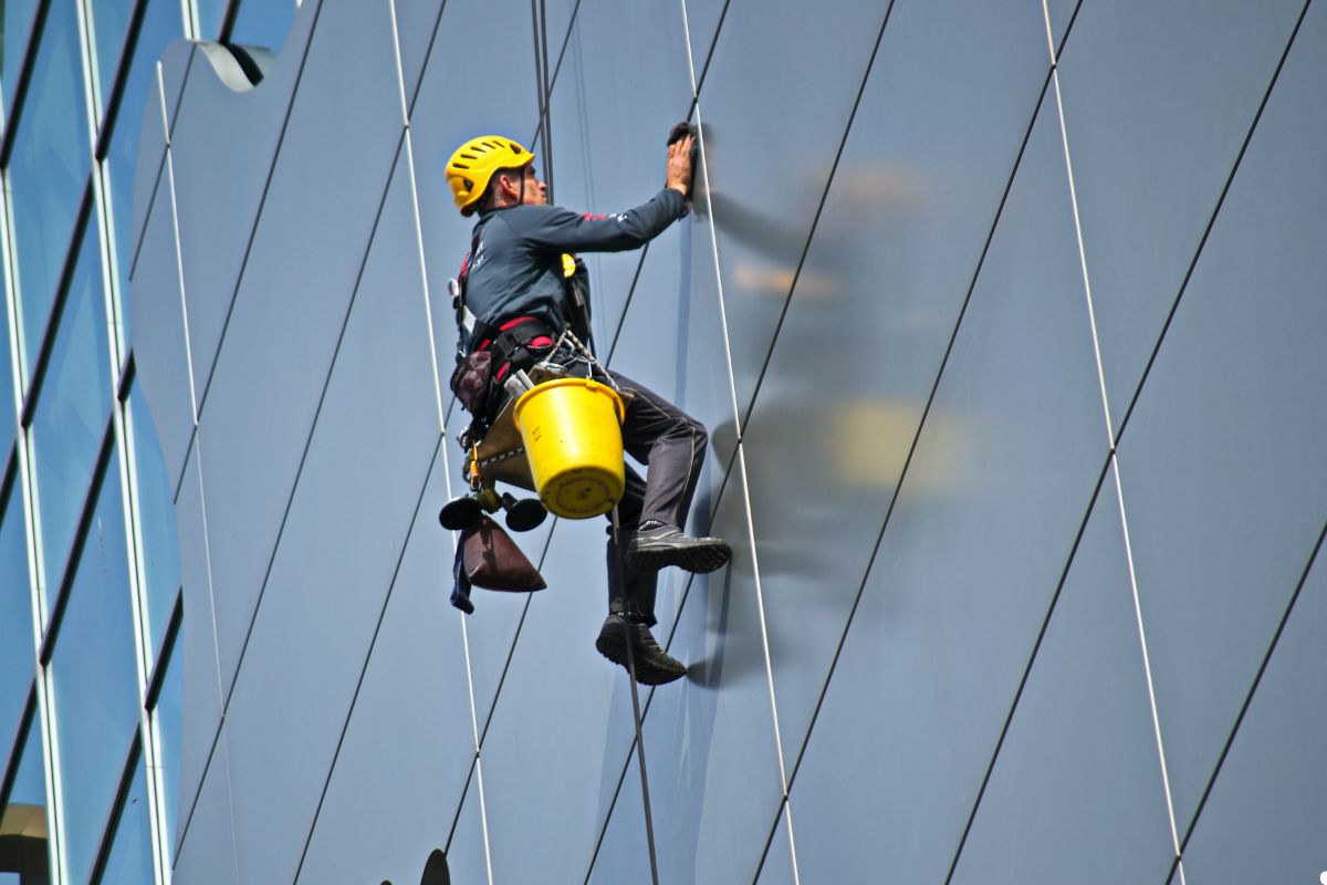  A man in safety gear climbs the side of a building, demonstrating construction work at a height. 